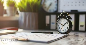 A clock and calendar sitting on a desk representing timekeeping.